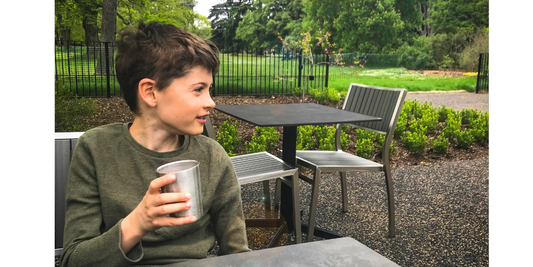 Kind hält KiNDKiT Edelstahl Becher im Park nachhaltig BPA-frei