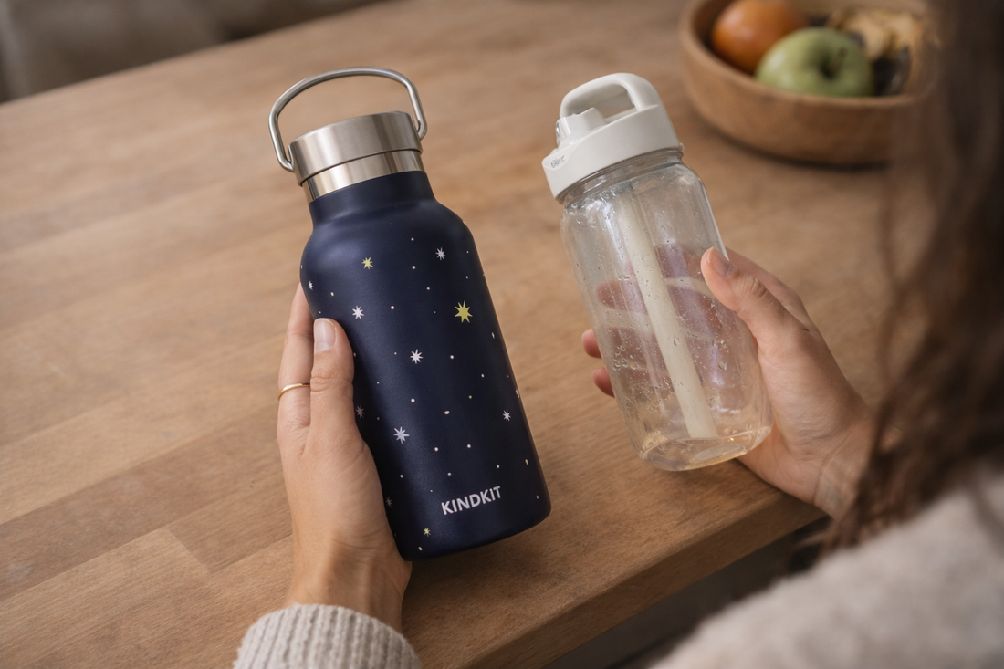 Hand hält KiNDKiT Edelstahl Trinkflasche Vergleich Plastik Kinderbecher