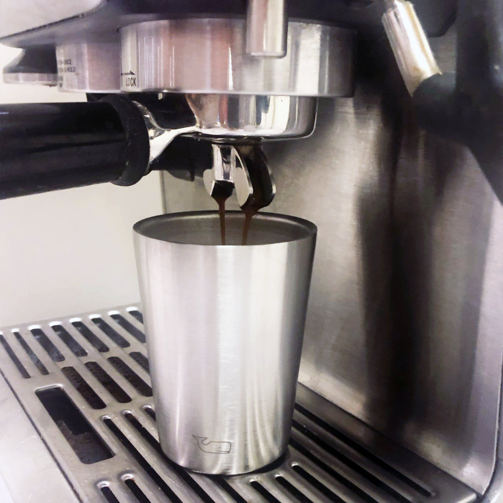 Espresso pouring from the machine into a KiNDKiT stainless steel cup with a whale-fin embossing